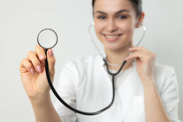 Happy doctor keeping stethoscope in hand indoors - Photo, Image