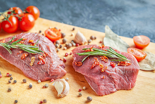 raw meat with spices, cherry tomatoes and garlic on a wooden cutting board - Photo, Image