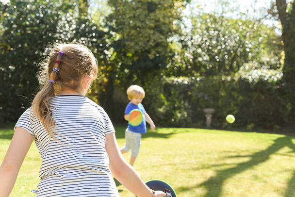 Kinder spielen draußen vor einem Bruder und einer Schwester ein Ballspiel im Garten - Foto, Bild