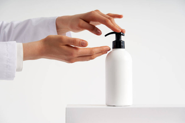 Woman hands pushing pump plastic soap bottle with copy space, using wash hand sanitizer gel pump dispenser. killing germs, bacteria and virus - Photo, image
