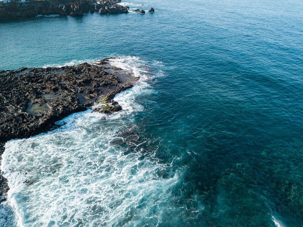 Aerial drone photo top view of Ocean waves meet or occur with a large rock cliff. waves are breaking on the rocks aerial view. Amazing nature landscape - Foto, Imagen