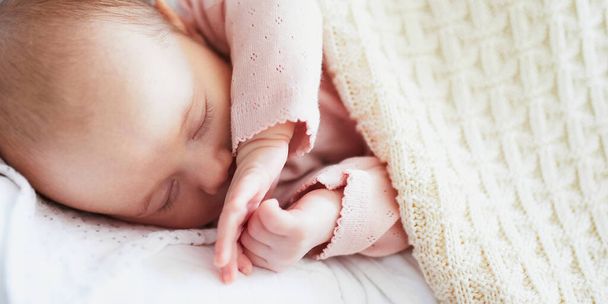 Adorable baby girl sleeping under knitted blanket in nursery - Фото, изображение