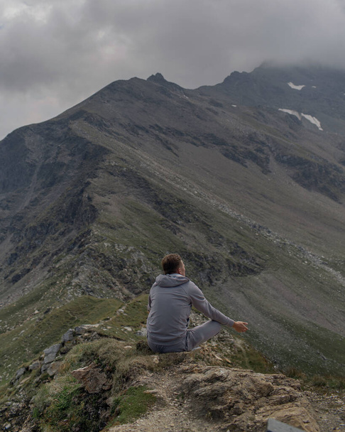 Young man meditates on the top of Alpine mountain - Fotoğraf, Görsel