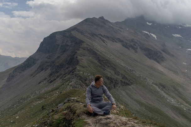 Young man meditates on the top of Alpine mountain - Foto, Bild