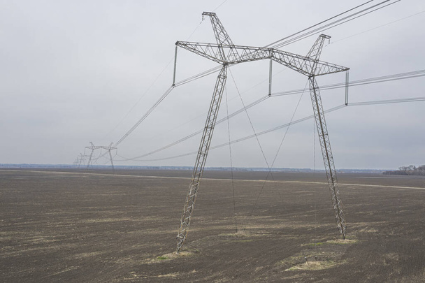 Metal supports of power lines passing through agricultural fields. - Photo, Image