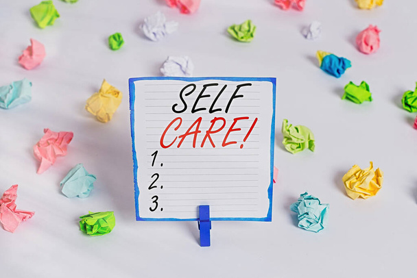 Conceptual hand writing showing Self Care. Business photo text practice of taking action preserve or improve ones own health Colored crumpled paper empty reminder white floor clothespin. - Photo, Image