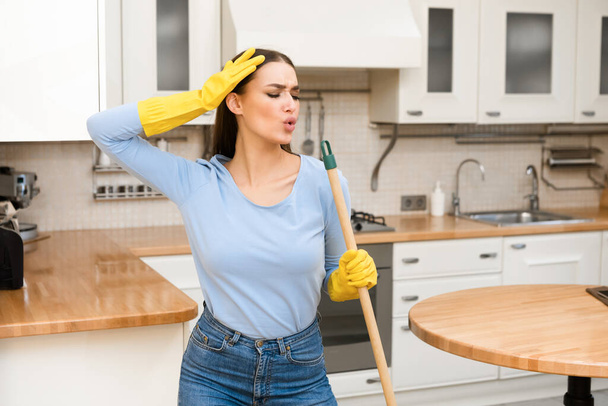 gelukkig jong vrouw schoonmaken keuken vloer zingen op dweil - Foto, afbeelding