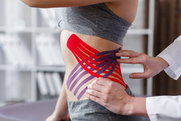 Weight loss concept.Kinesiology taping.Therapist applying kinesiology tape to patient belly.Anti-cellulite procedure for slim tummy.Fat lose,cellulite removal, sport physical therapy,recovery concept - Photo, Image