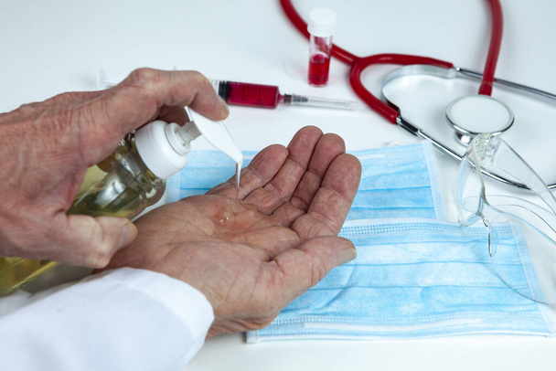 Arzt verabreicht Desinfektionsmittel an seine Hände, um die Ausbreitung des Coronavirus nach der Arbeit auf der Krankenhausstation zu stoppen - Foto, Bild