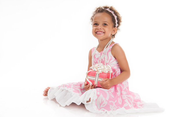 Happy little girl with a gift in mulatta hands. - Фото, зображення