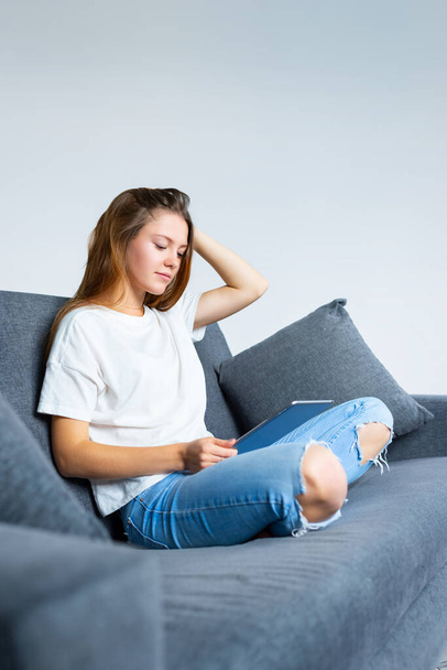 Teenage with digital tablet computer in hands, sitting on a sofa - distance learning - Foto, Imagen