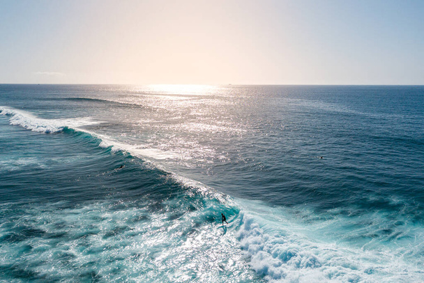 aerial view of a surfer riding a surf at sunset, Surfer ride on waves in ocean sunset, top view - Foto, imagen