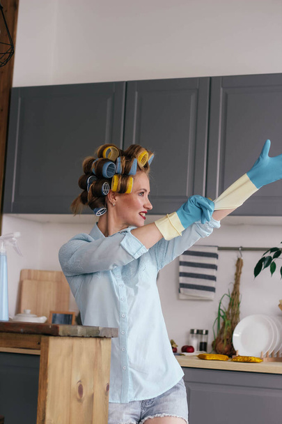 Girl in curlers puts on gloves - Photo, image