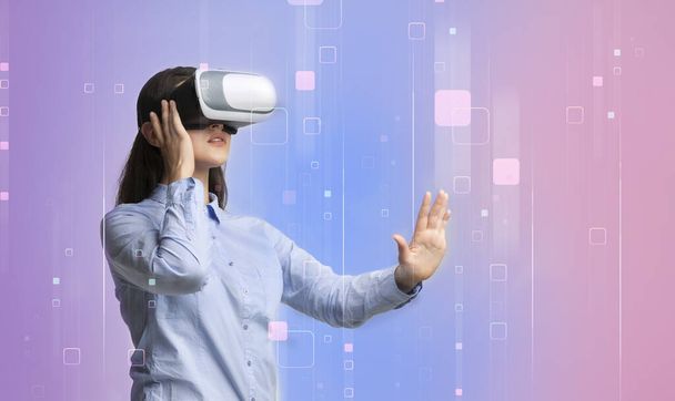 Millennial girl in virtual reality headset touching imaginary screen on color background, collage with empty space - Photo, Image