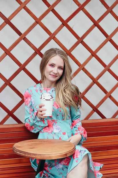 young blond woman sitting in a cafe with coffee and whipped cream - Foto, Imagem