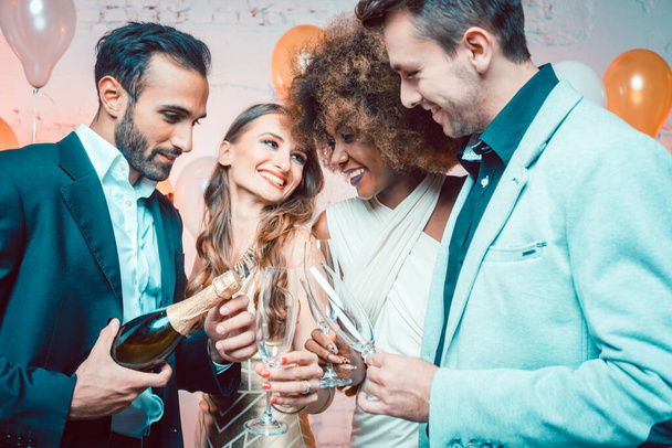 Gente de fiesta en un club celebrando el nuevo año sirviendo champán
 - Foto, Imagen