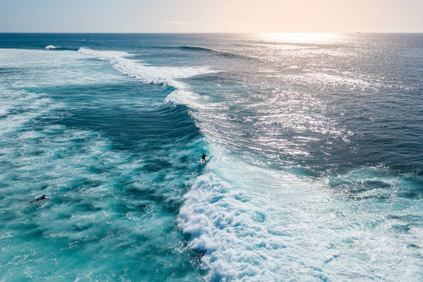 aerial view of a surfer riding a surf at sunset, Surfer ride on waves in ocean sunset, top view - Foto, immagini