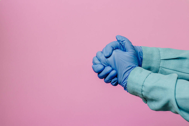Hands of a girl in blue gloves on a pink background - Foto, afbeelding