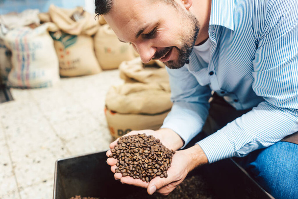 Чоловік зі свіжообсмаженими кавовими зернами
 - Фото, зображення