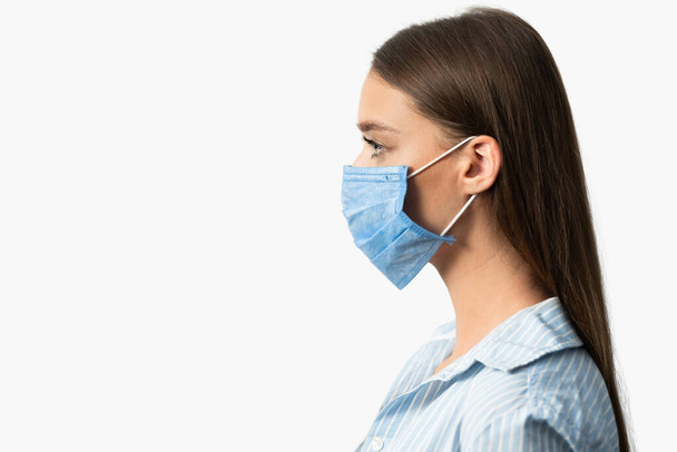 Κορίτσι με την ιατρική μάσκα Posing On White Studio Background, Side-View - Φωτογραφία, εικόνα