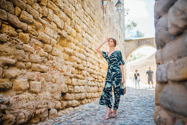 A girl in a straw hat and dress walks in Carcassonne on a Sunny day - Фото, изображение