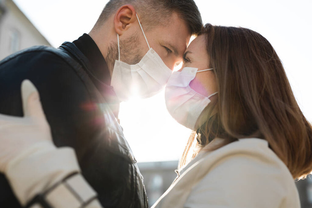 Couple in love, man and woman kissing each other in protective medical mask on face. Guy, girl against pandemic coronavirus, virus protection. Covid19 - Photo, image