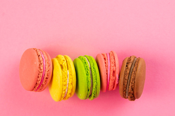 Colorful macaroons stand on a pink background. Top views with clear space - Valokuva, kuva