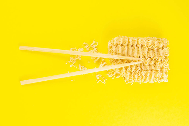 Instant noodles with wood sticks. Asian fast food on a yellow background close-up. Top views. - Photo, Image