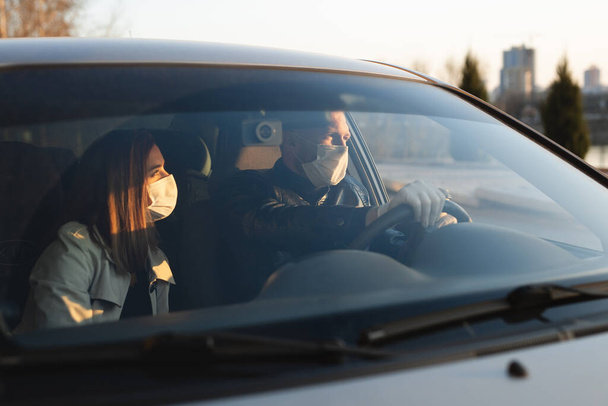 Un homme et une femme portant des masques médicaux et des gants en caoutchouc pour se protéger des bactéries et des virus lorsqu'ils conduisent une voiture. des hommes masqués dans la voiture. coronavirus, covide-19
 - Photo, image