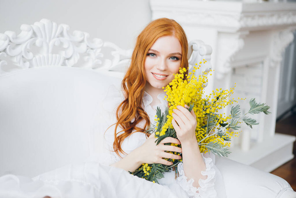 Portrait of a red-haired beautiful girl with a Mimosa in a long white dress. Spring concert. Toning. - Fotoğraf, Görsel