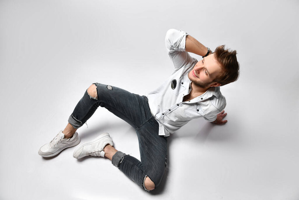 Hipster person in shirt, bracelets, gray jeans and sneakers. He is smiling and looking up, posing isolated on white. Close up - Foto, imagen