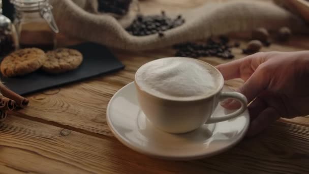 Personne méconnaissable met une tasse de cappuccino sur la table
 - Séquence, vidéo