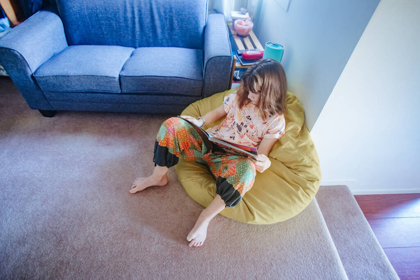 νεαρή έφηβη που διαβάζει στο σπίτι, κατ 'οίκον εκπαίδευση, διαμονή στο σπίτι απομόνωση  - Φωτογραφία, εικόνα