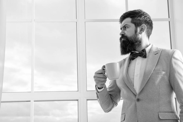 modern businessman. thoughtful bearded man drink coffee. businessman in modern formal outfit. modern life. business man at window. future success. morning inspiration. copy space. modern office - Фото, изображение
