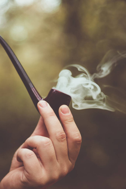 Közelkép füstölgő dohánypipa homályos háttér szabadban - Fotó, kép