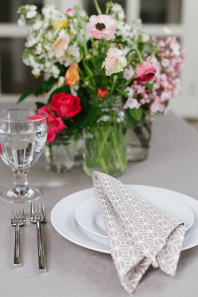 Placa de refeição configurada com roupa de cama de cor natural, placa branca e flores recém-cortadas
 - Foto, Imagem