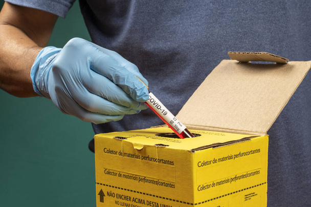 γιατρός πετώντας σωλήνα κενού σε ένα κουτί απόρριψης μολυσματικών αποβλήτων - Φωτογραφία, εικόνα