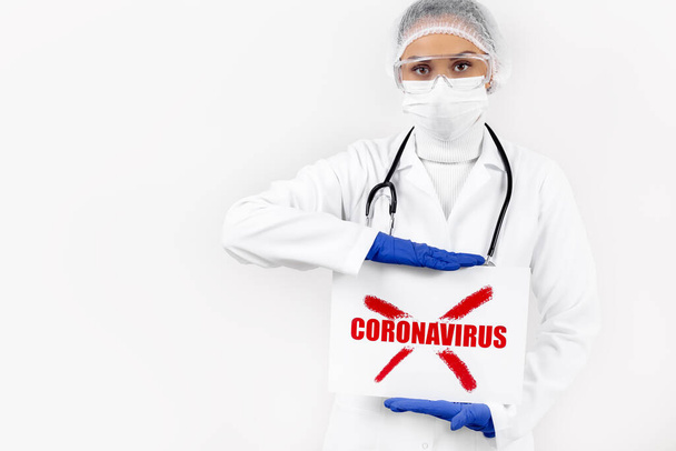 Pewny siebie lekarz trzymający plakat ze znakiem stop COVID-19 nad białym piekarni. Epidemia i koncepcja pandemii koronawirusów. - Zdjęcie, obraz