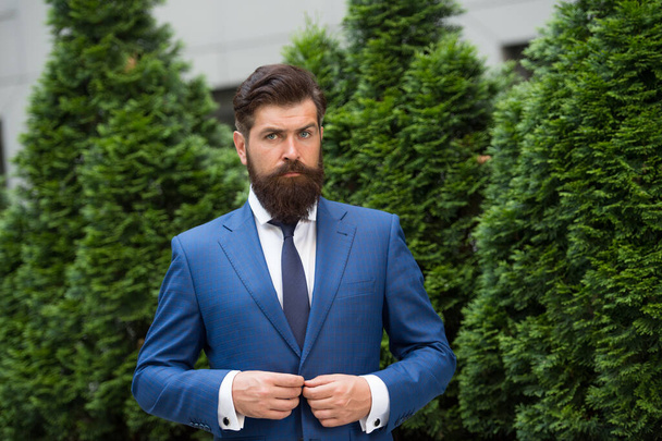 自信のある男が街の外に立ってる。ヒノキの木の近くで成熟した髭の男。屋外で成功した実業家。自信のあるビジネスマン。ハンサムな成熟した起業家 - 写真・画像