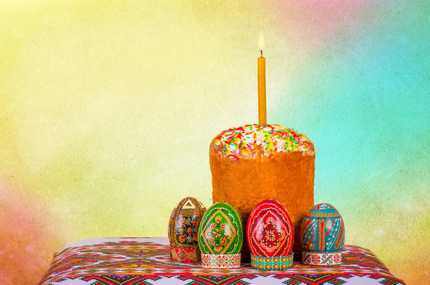 Пасхальний торт та великодні яйця стоять на вишивці та палаючій свічці
 - Фото, зображення