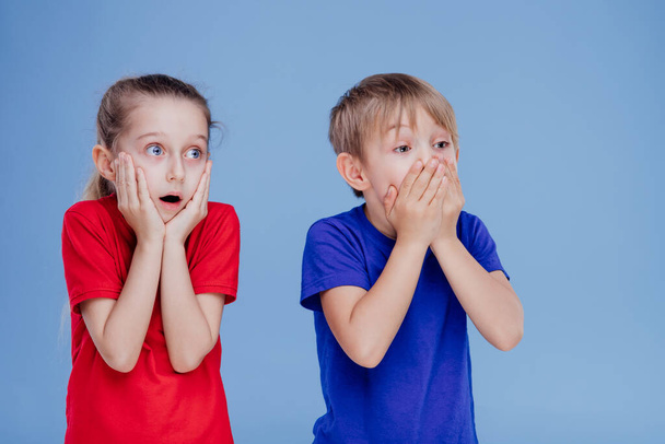 two scared children with hands on face isolated on blue - Photo, Image