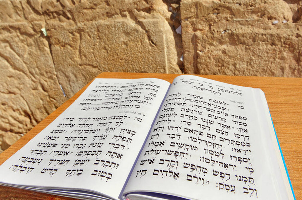 Το Βιβλίο των Ψαλμών του Βασιλιά Δαβίδ στα εβραϊκά ενάντια στο Τείχος των Δακρύων. Ο Μεσσίας θα είναι πάτριχος απόγονος του Βασιλιά Δαβίδ, και θα συγκεντρώσει τους Εβραίους πίσω στη Γη του Ισραήλ.. - Φωτογραφία, εικόνα