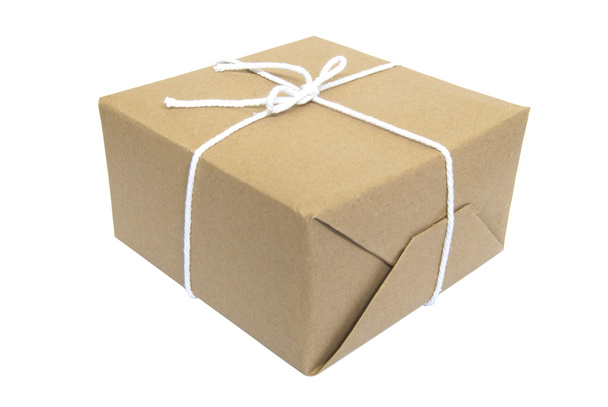 Подарочная упаковка в обертке из коричневой бумаги, завязанная бечевкой на белом фоне
 - Фото, изображение