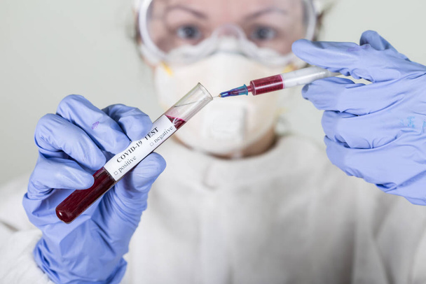 Doctor in protective wear holding test tube with blood for Coronavirus COVID-19 analyzing. Vaccine from, flu, coronavirus, ebola. - Foto, Bild