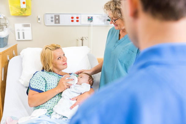 Enfermeira olhando para a mulher alimentando leite para a babá no hospital
 - Foto, Imagem