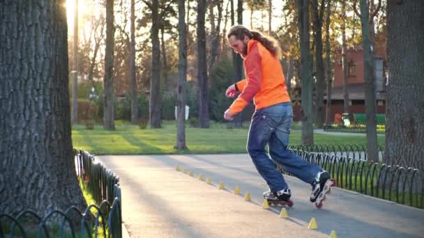 Roller skate training in sunny weather in autumn. Active and athletic lifestyle in slow motion. Professional skater trains his bypass skills between special cones and makes complex technical turns. - Footage, Video