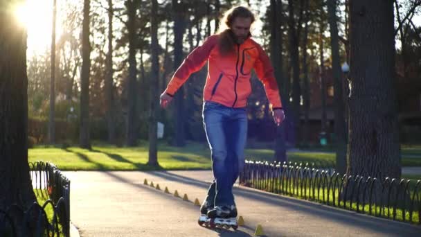 A professional male roller rides great backwards, crossing his legs and riding between the cones. A man performs a technical roller skate ride in slow motion. - Footage, Video