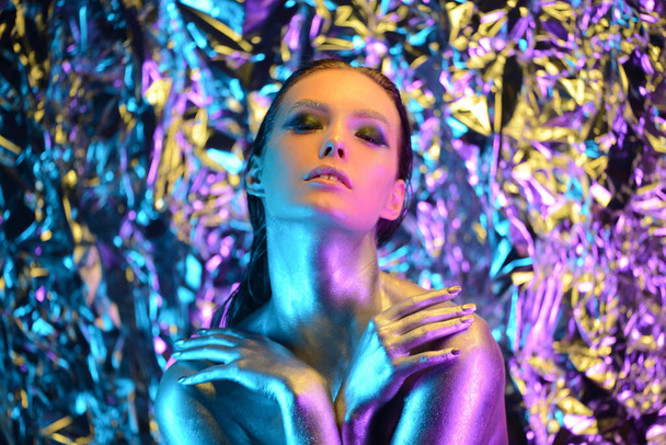 High Fashion modelka v barevných zářivých neonových světlech pózující ve studiu, portrét krásné ženy, módní zářící metalický make-up, stříbrné náušnice. Živý neonový makeup. Široký úhel - Fotografie, Obrázek