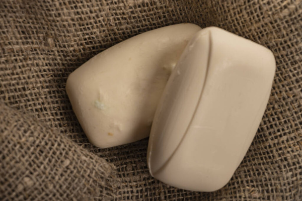 Deux morceaux de savon de toilette sur un fond de tissu à texture grossière. Le lavage fréquent des mains avec du savon est une prévention de l'infection par COVID-19. Gros plan
 - Photo, image