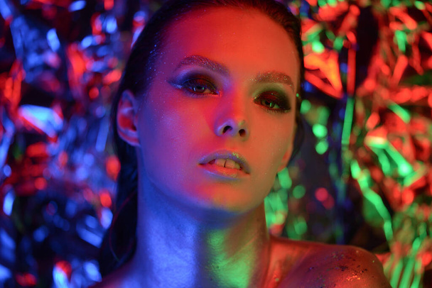 Mode-Modell metallische silberne Lippen und Gesicht Frau in Neon uv blauen und lila Lichtern, posiert im Studio, schönes Mädchen, glühendes Make-up, buntes Make-up. - Foto, Bild